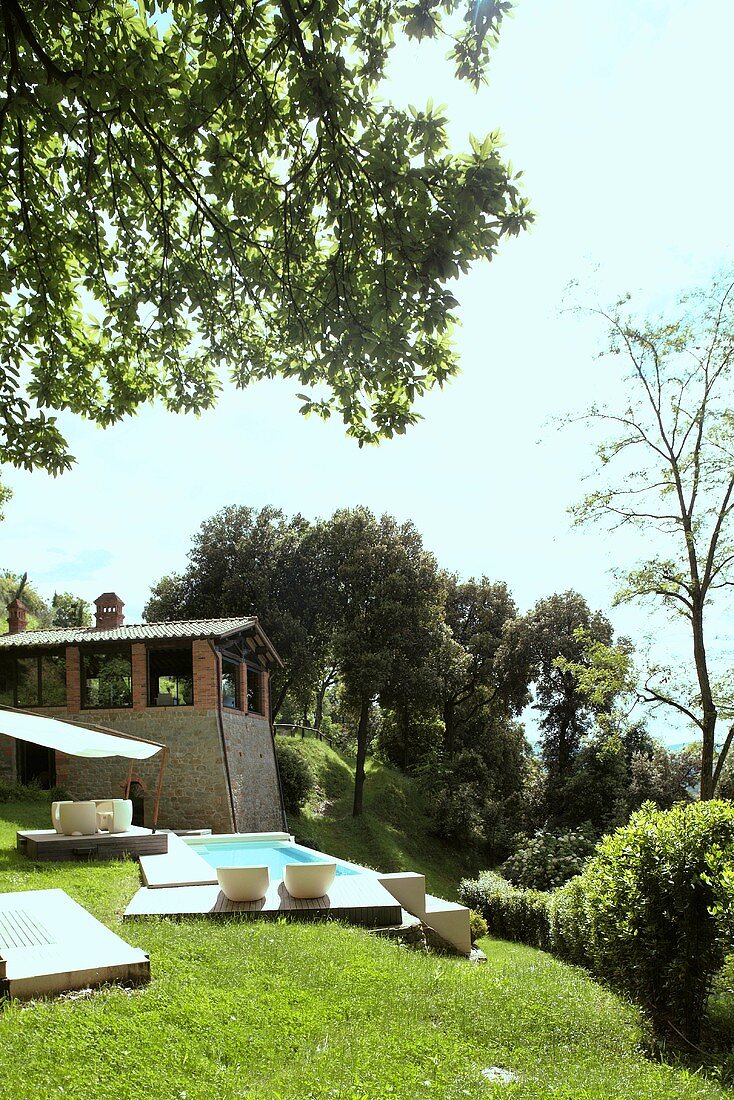 Pool in a garden with white patio furniture and view of a country home