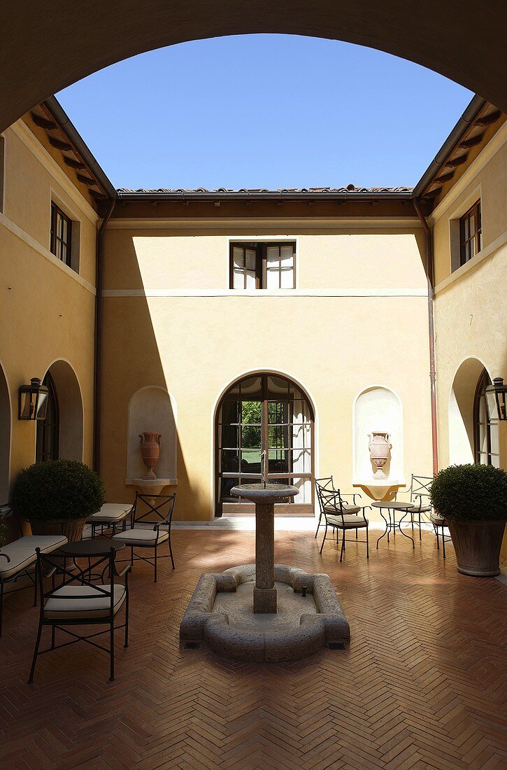 Sonnige Stimmung im Mediterraner Innenhof einer Villa mit Steinbrunnen