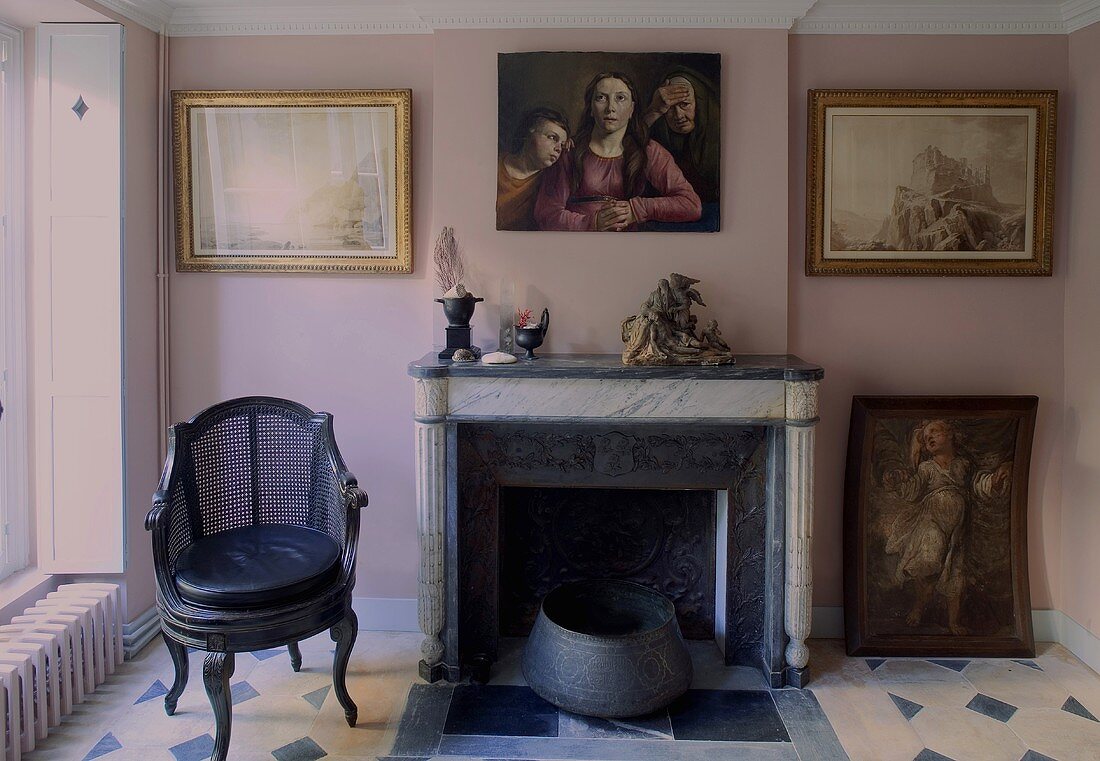 Kaminzimmer im Altbau mit Bildern an rosa Wand und Fliesenboden mit Muster
