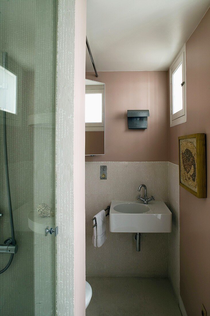 Rosafarbenes Bad mit weißem Waschbecken und kleinen Fenstern