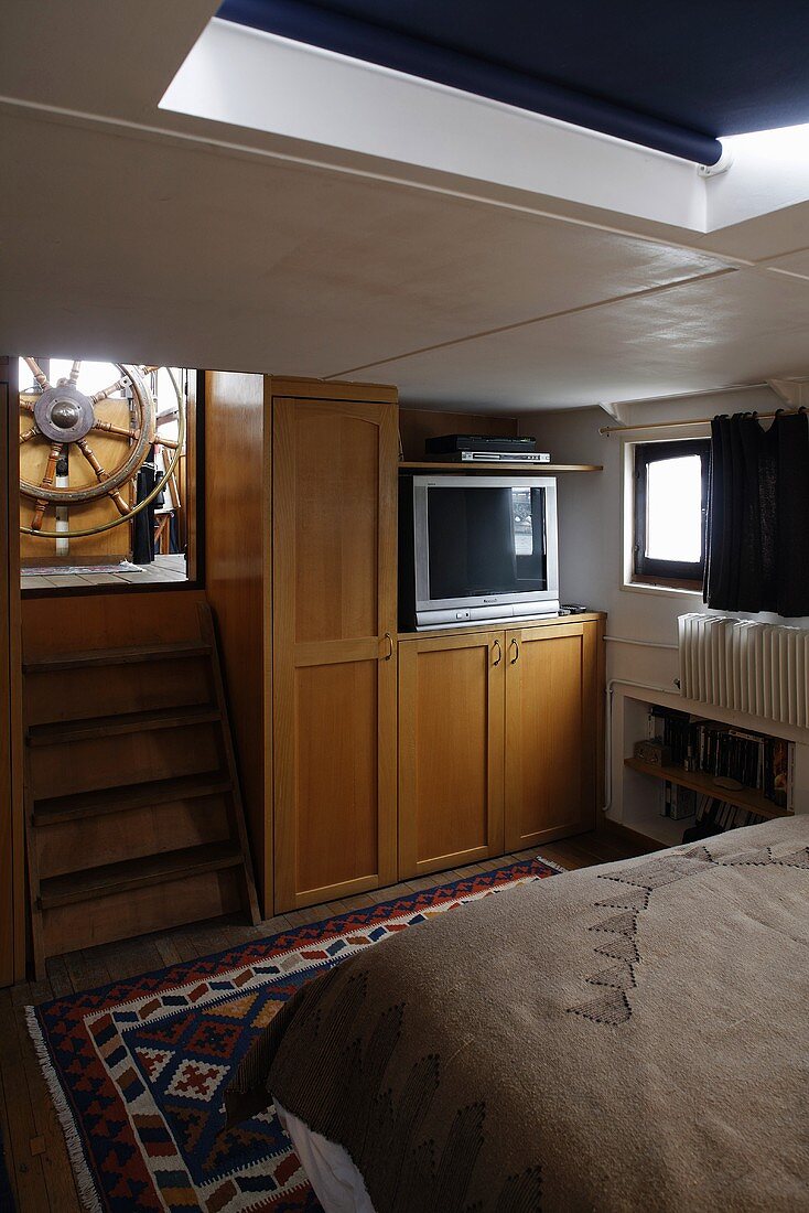 Cabin in a house boat with a built-in cupboard and stairs with a view of the steering wheel