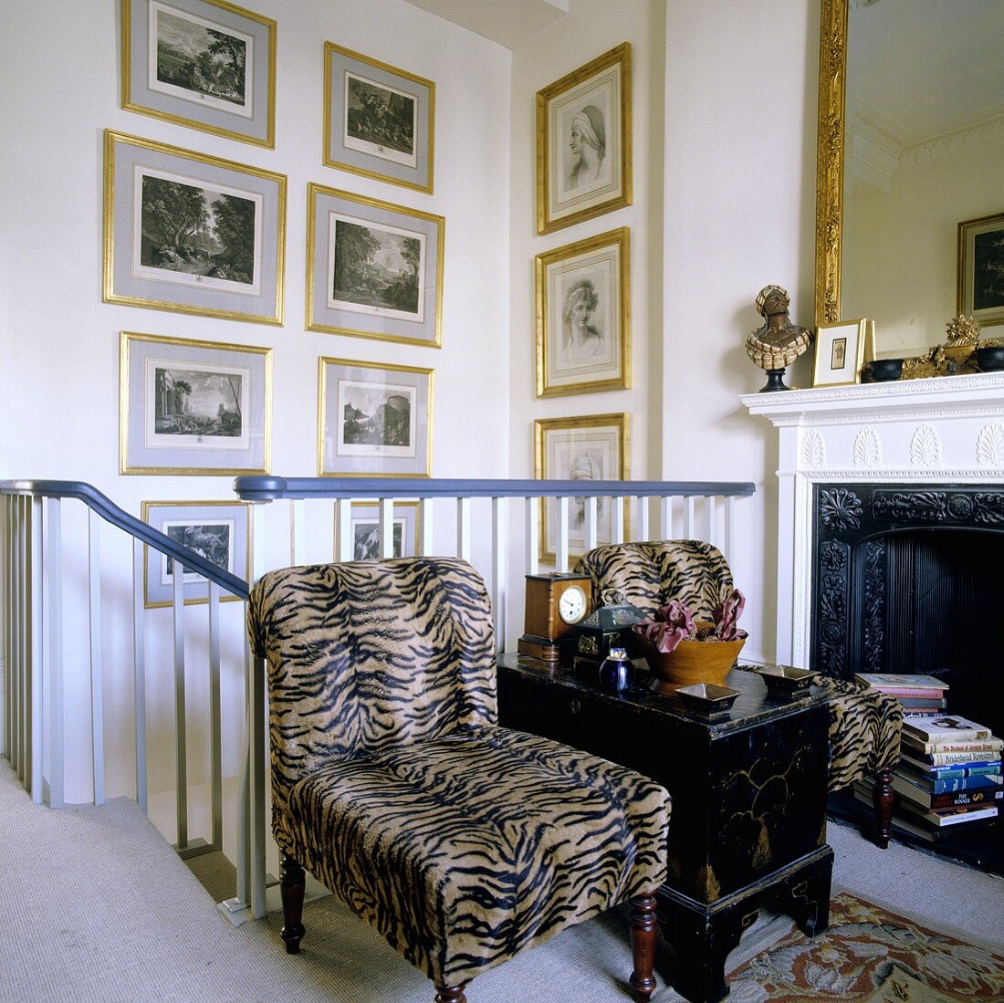 Sessel mit Fellbezug am Treppengeländer vor dem Kamin und Bilder mit Goldrahmen an Treppenraumwand