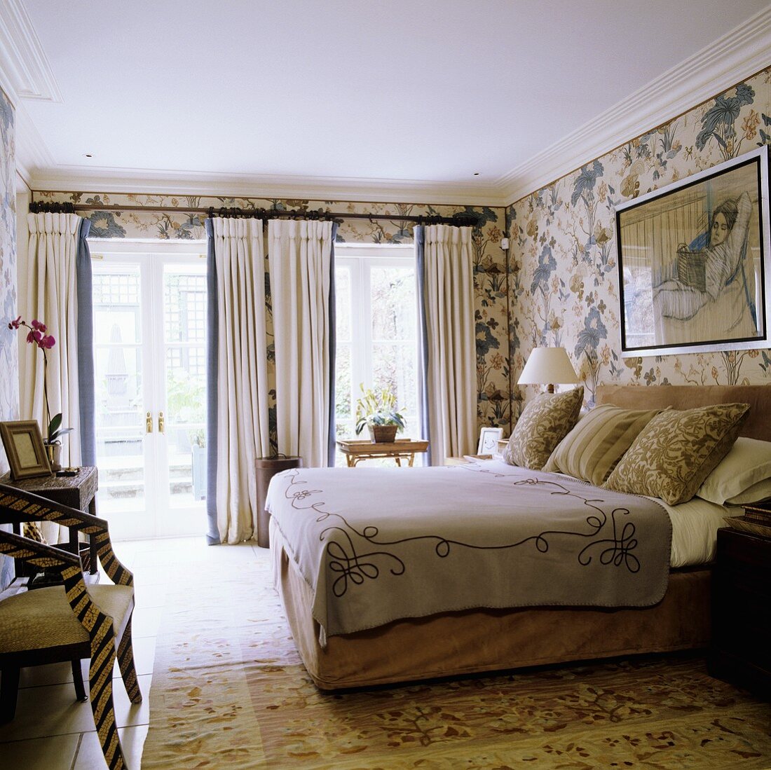 Schlafraum im englischen Stil mit Fenstertüren und Doppelbett vor Tapete mit Blumenmuster