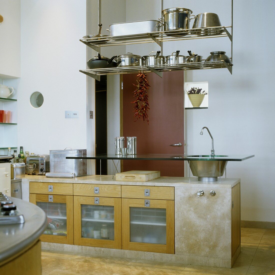 Küchenblock aus Beton mit Thekenaufsatz aus Glas mit integrierter Spüle und abgehängtem Regal