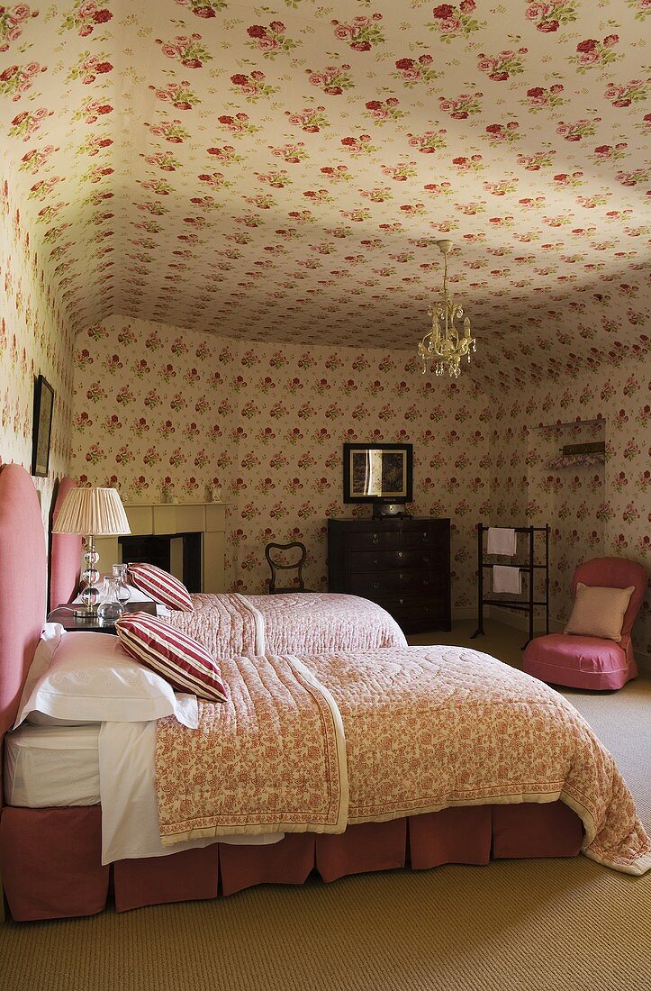 A bedroom with single beds and a floral pattern on the walls and ceiling