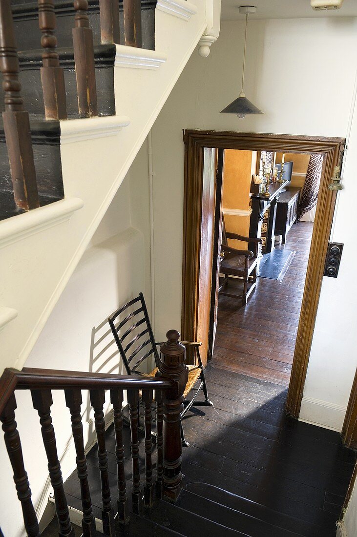Altes Treppenhaus - dunkles Holzgeländer und Holzboden mit Blick durch Türöffnung in Wohnraum