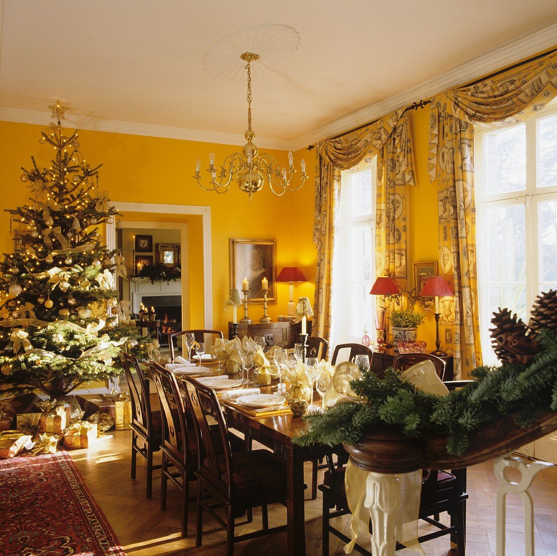 Weihnachtsfeier im Esszimmer eines englischen Landhauses mit raumhohen Fenstern und gelben Wänden