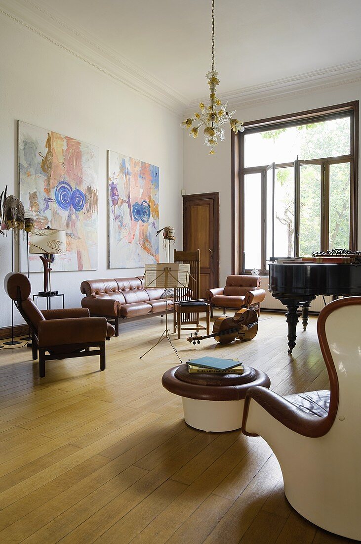 A music room with instruments and a leather sofa on floor boards