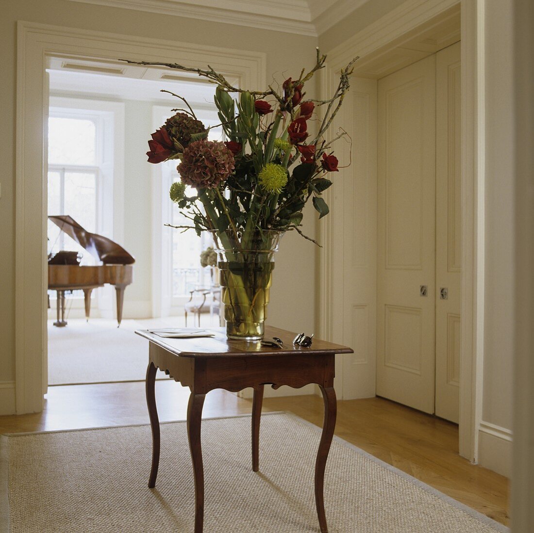 Beistelltisch im Rokokostil mit grossem Blumenstrauss im Vorraum mit Blick auf Klavier