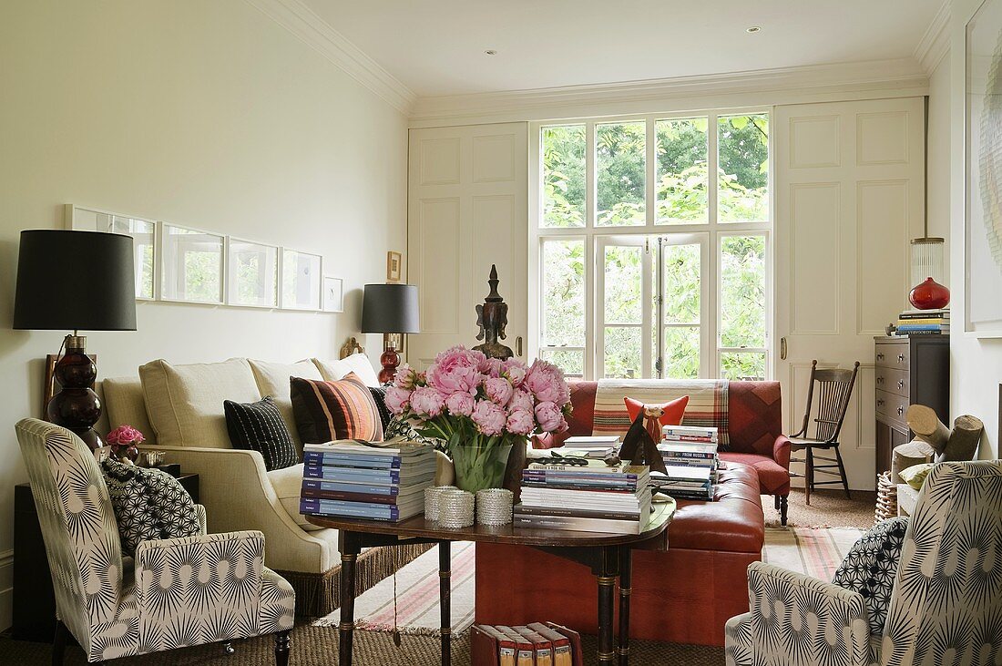 A living room with comfortable upholstered furniture and a sofa with occasional tables in front of a window with a view
