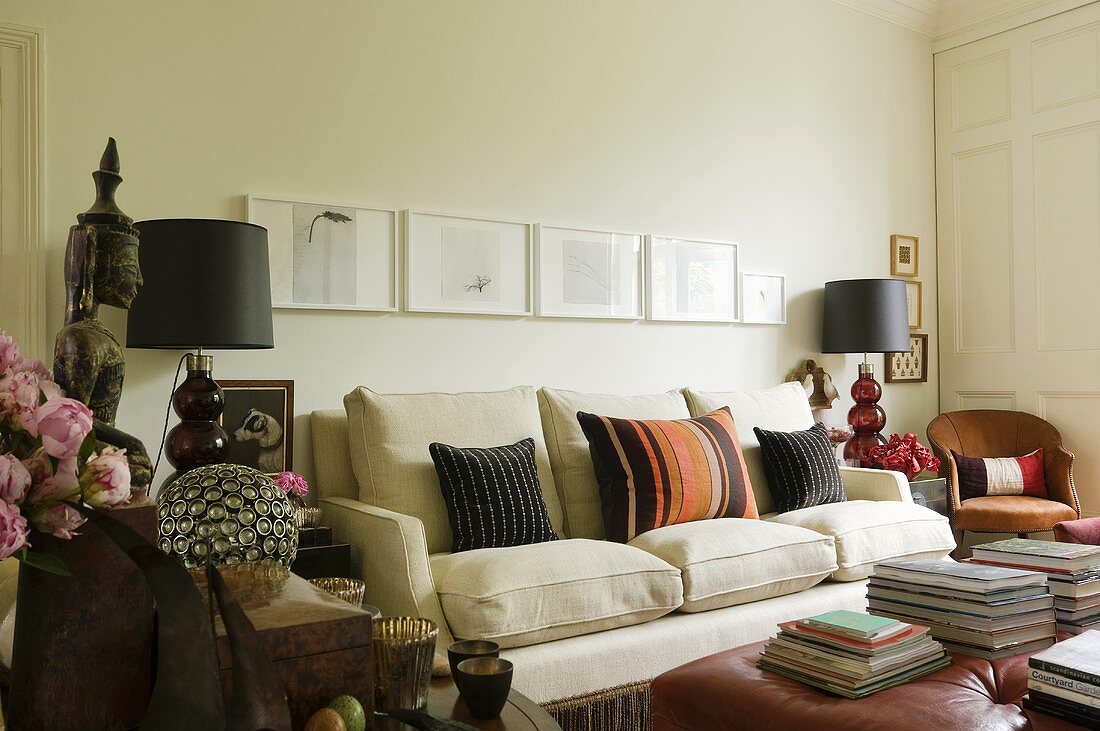 Table lamps with black shades next to a light-coloured upholstered sofa with cushions on it