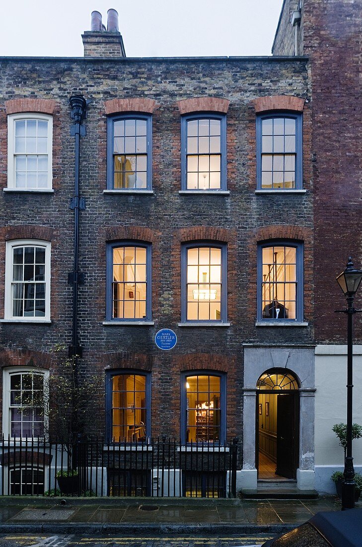 Englisches Wohnhaus in Dämmerstimmung mit Ziegelfassade und blauen Sprossenfenstern