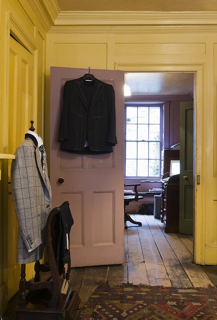 Schneiderpuppe mit Jacke im gelben Wohnraum und Blick in Arbeitsraum