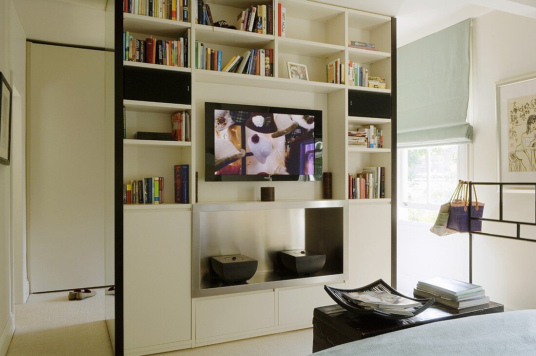A floor-to-ceiling shelf-cupboard as a room partition in an open-plan bedroom