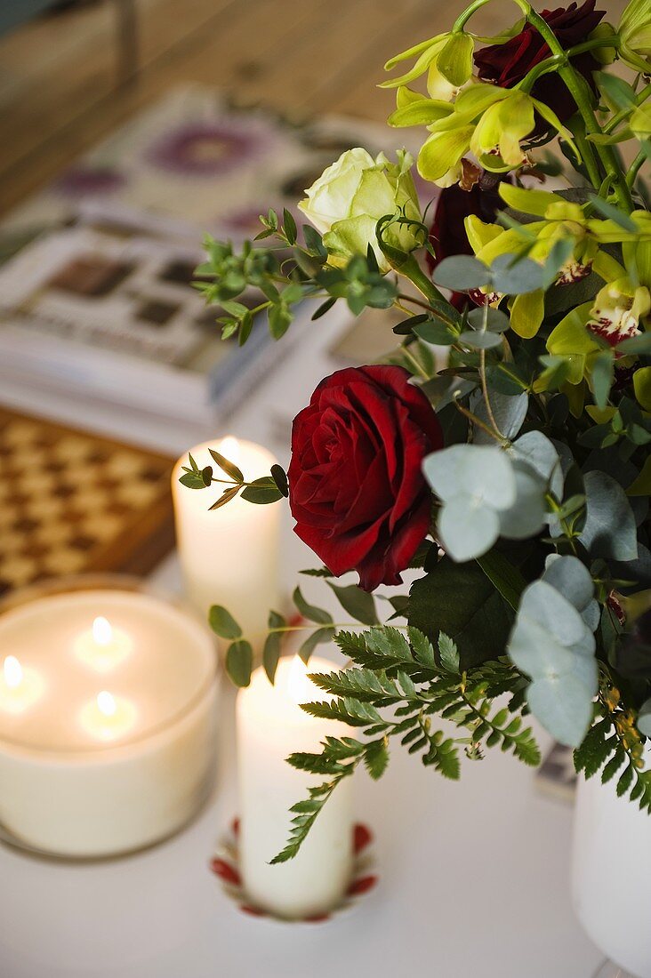 Candles and a bunch of flowers featuring red roses