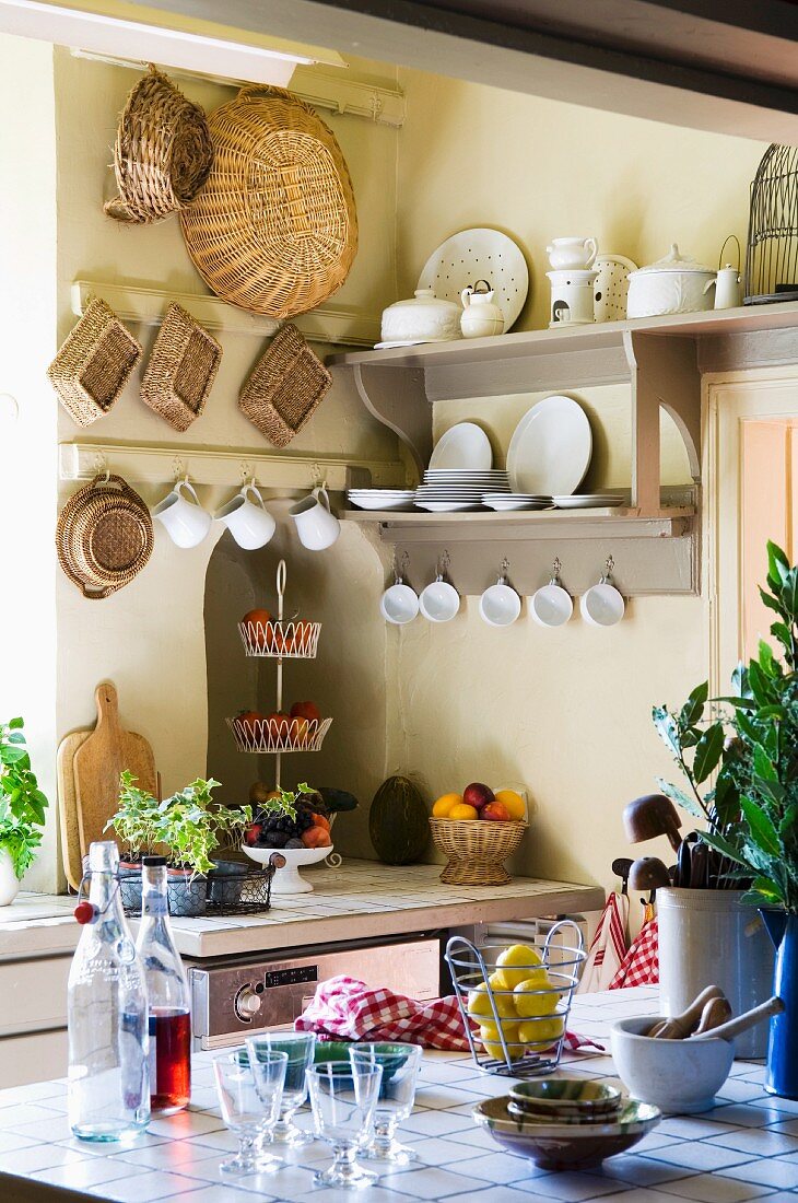 A view onto a light grey plate rack and hanging baskets in the kitchen of a country house