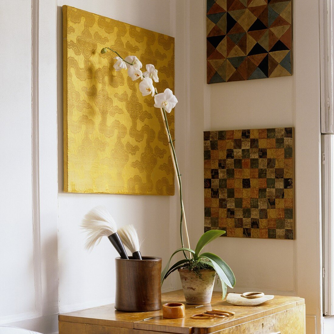 Geometric patterns on canvases in the corner of a living room and white orchids in a pot