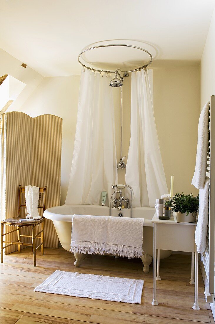 A bathroom in a country house with an antique bathtub with feet and a white shower curtain