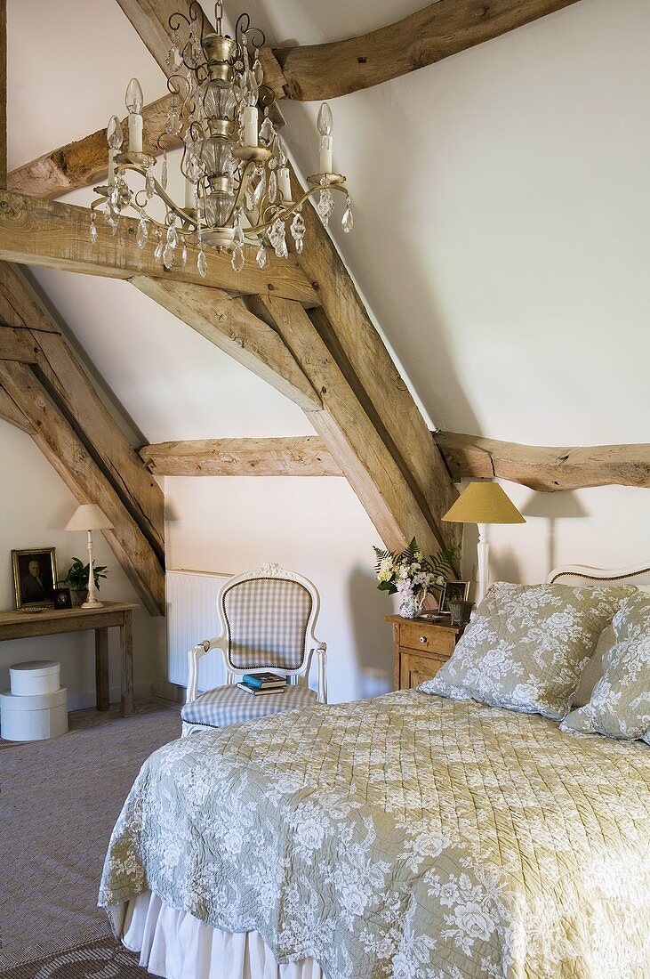 Französisches Bett und Kristallkronleuchter im rustikalem Landhausdachraum