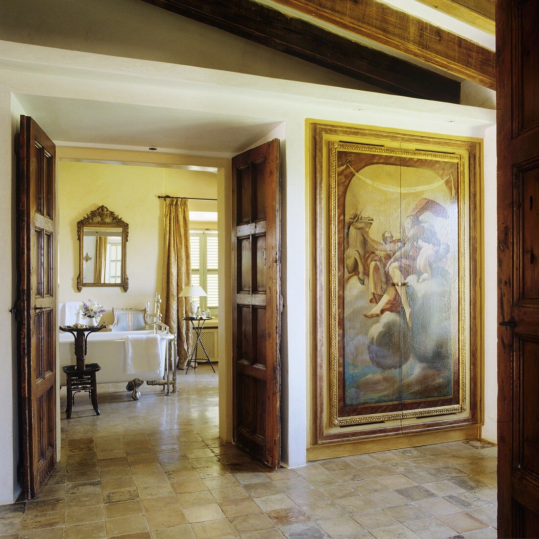 Eleganter Vorraum eines Landhauses mit bemaltem Einbauschrank und Blick durch offenstehende Holztür in das Bad
