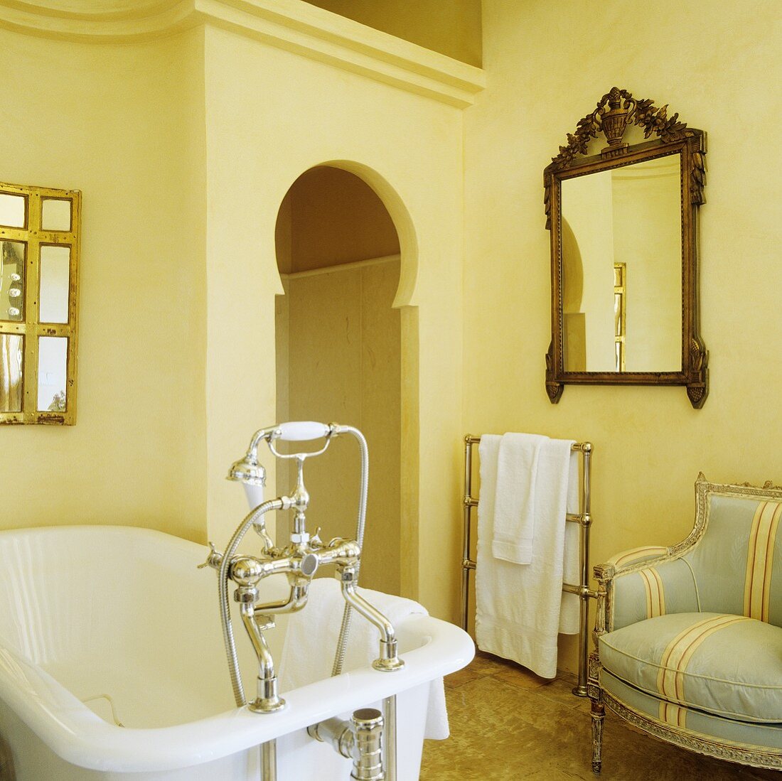 A bathtub with antique taps in front of a false front with an Oriental-style door opening