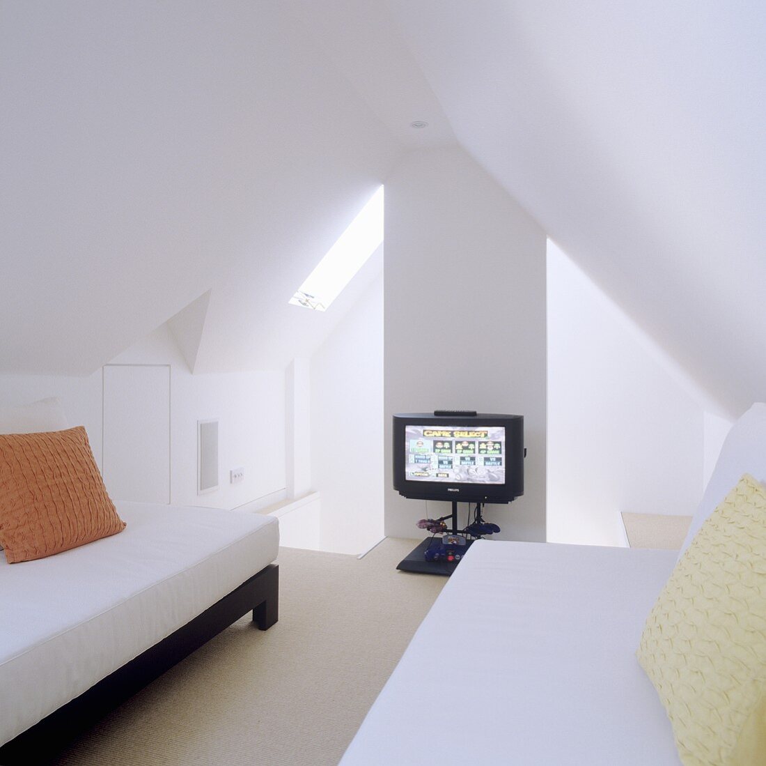 Minimalistischer Dachraum mit Einzelliegen unter Dachschräge und Fernseher