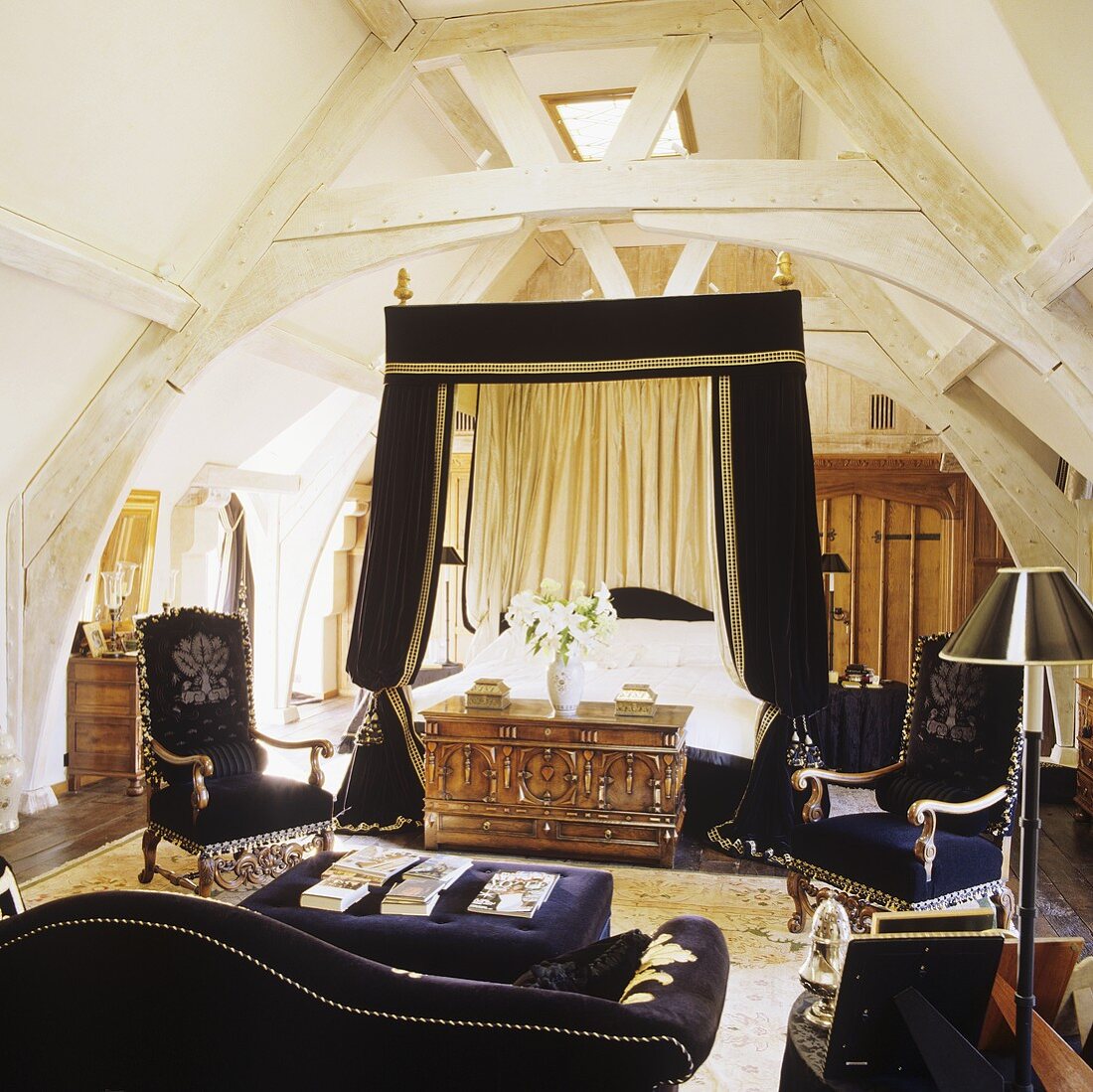 Himmelbett mit schwarzem Baldachin und schwarzer Sofagarnitur unter alter weisser Dachstuhlkonstruktion