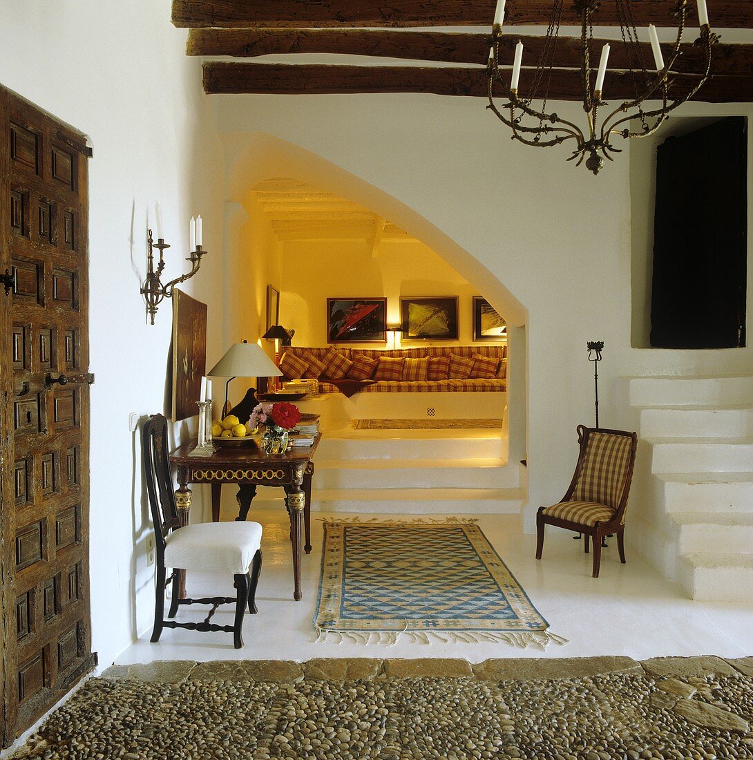 An elegant foyer in a finca with white concrete stairs and a view onto a comfortable padded seating corner