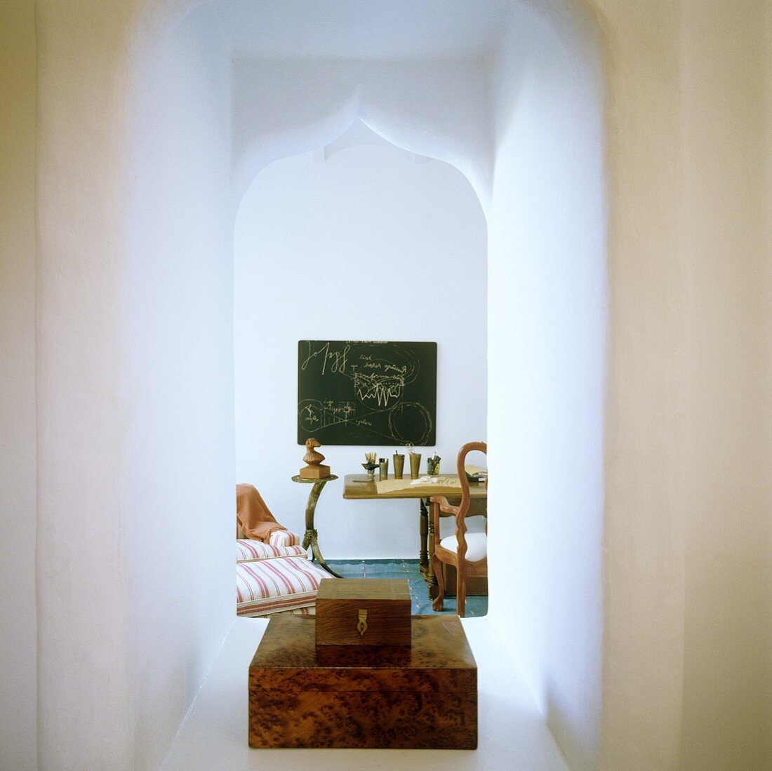 A stack of wooden boxes in a Moorish archway with a view onto a dining table