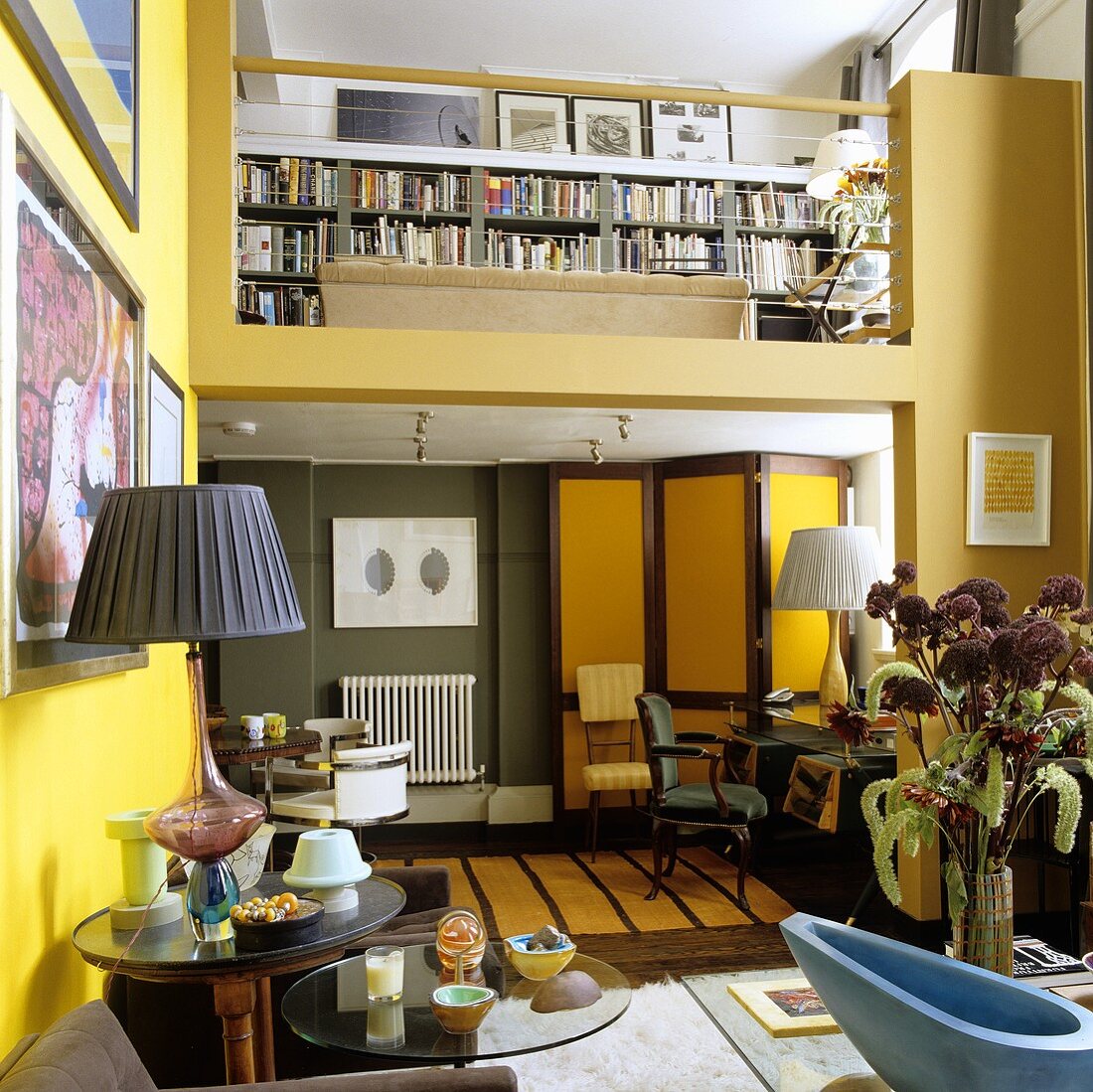 Maisonettewohnung - Wohnraum mit gelbgetönten Wänden und Blick auf Galerie mit Bücherregal