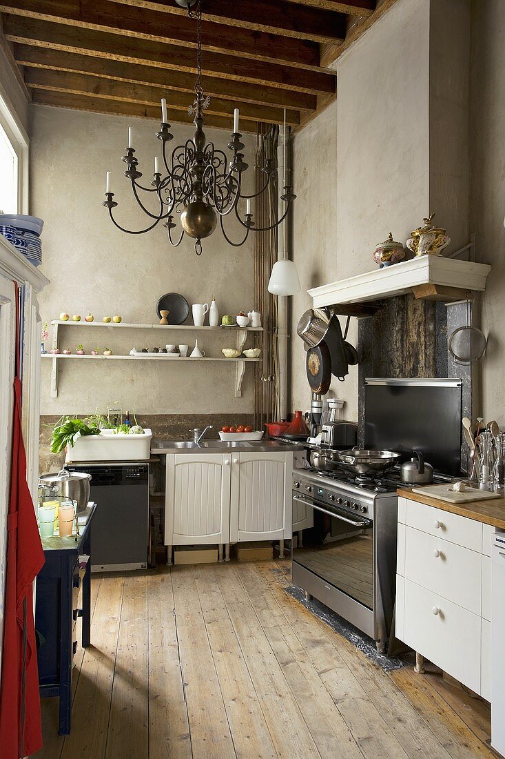 Alte Küche im Stilmix vor grauen Wänden und Kerzenleuchter an rustikaler Holzbalkendecke