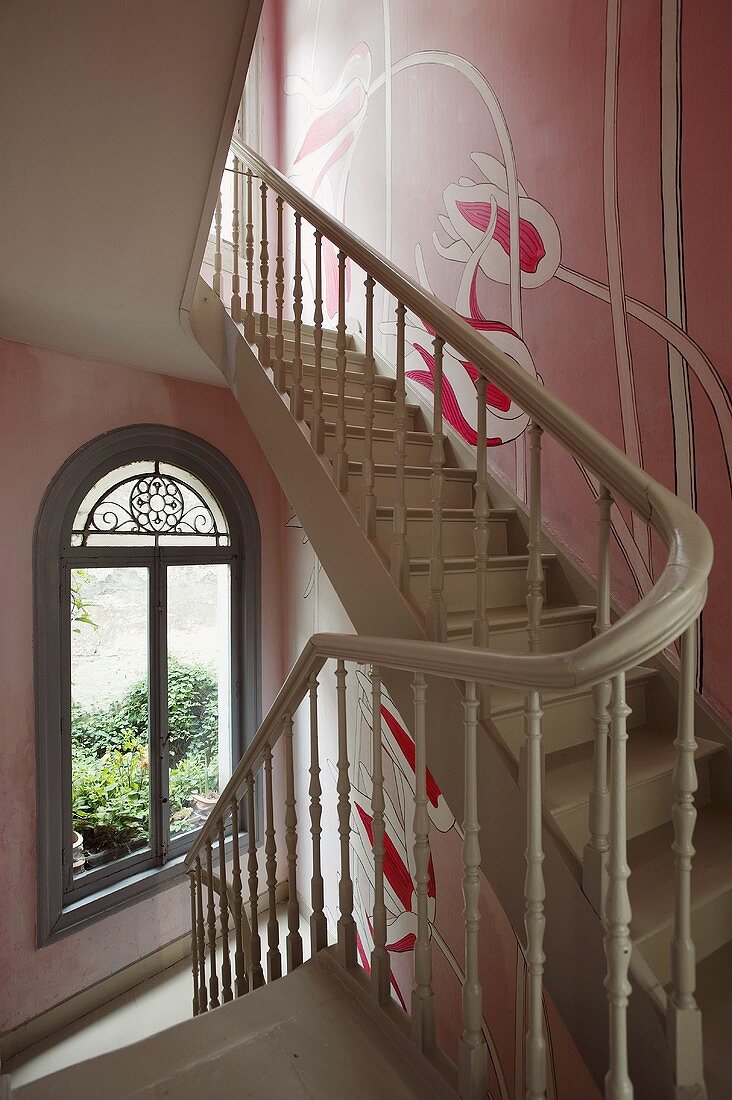 A stairway with grey-painted stairs and a flower painted on a pink wall