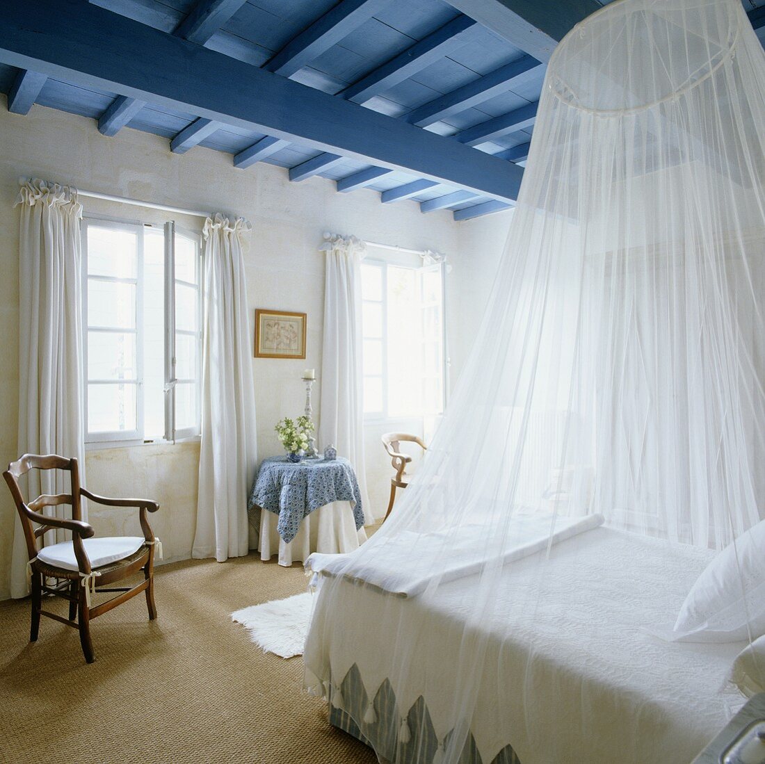 Weisser Himmel über französisches Bett unter blauer Holzdecke im ländlichen Schlafraum