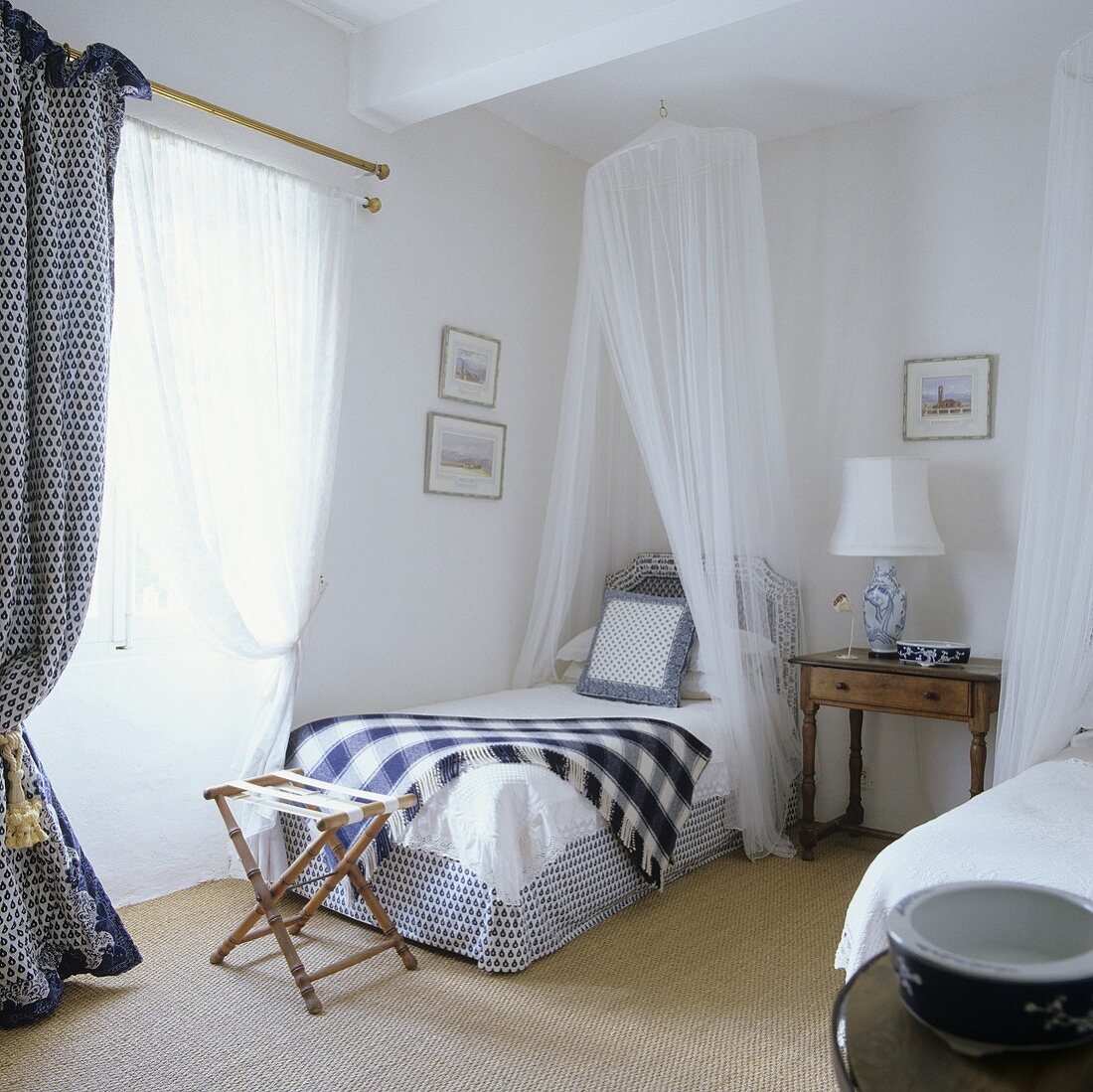 A single bed with a canopy and a stool in a bedroom in a Provençal country house