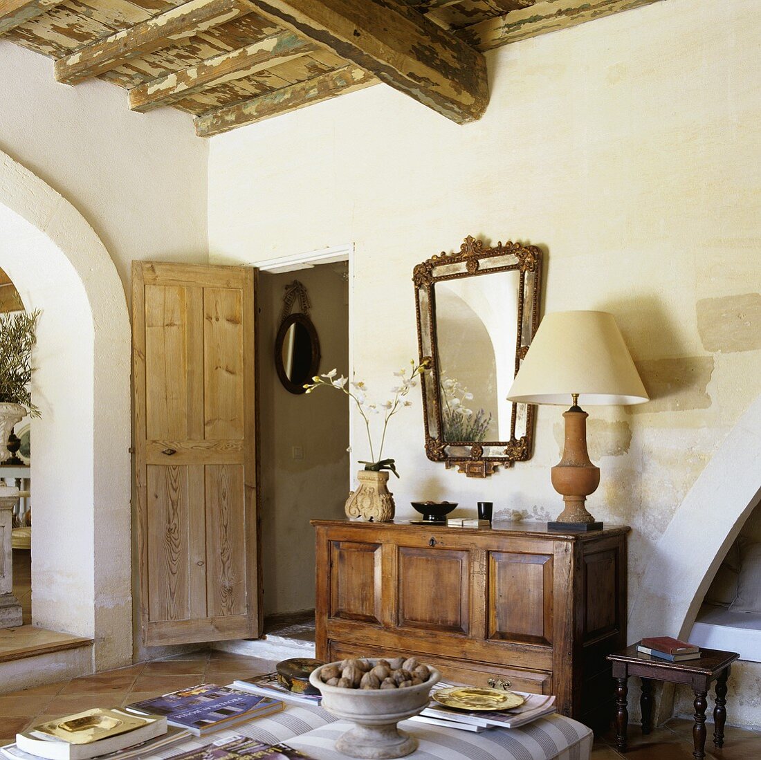 Wohnraum im provenzalischem Landhaus mit rustikaler Holzdecke und Sideboard neben offenstehender Tür
