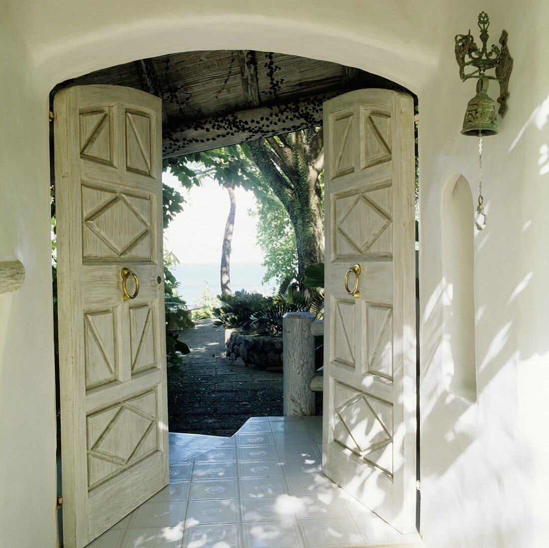 Offenstehende Haustür einer tropischen Villa mit Blick in den Garten und auf das Meer