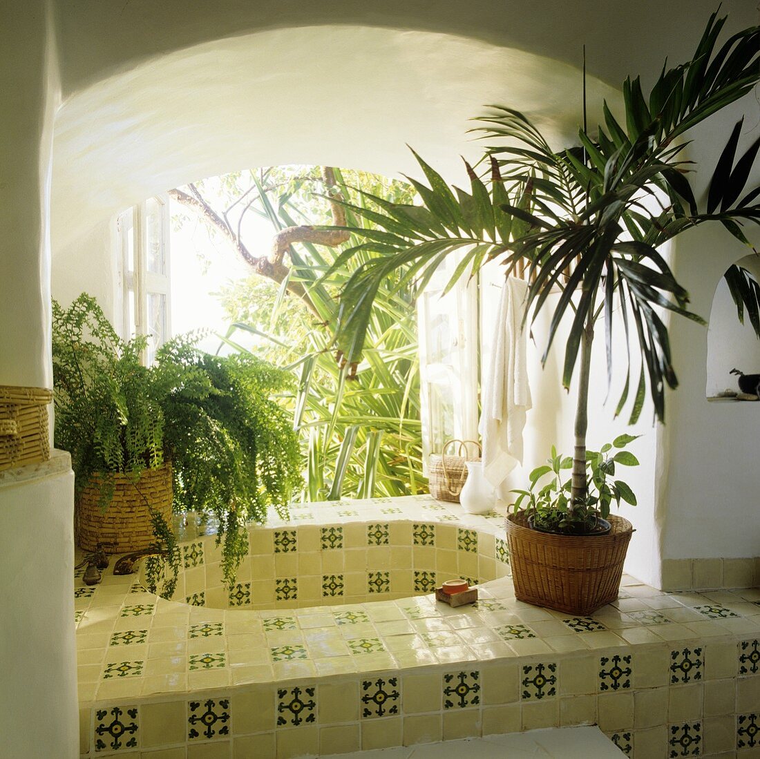 A tiled sink in a arched wall niche with a window and view of the garden
