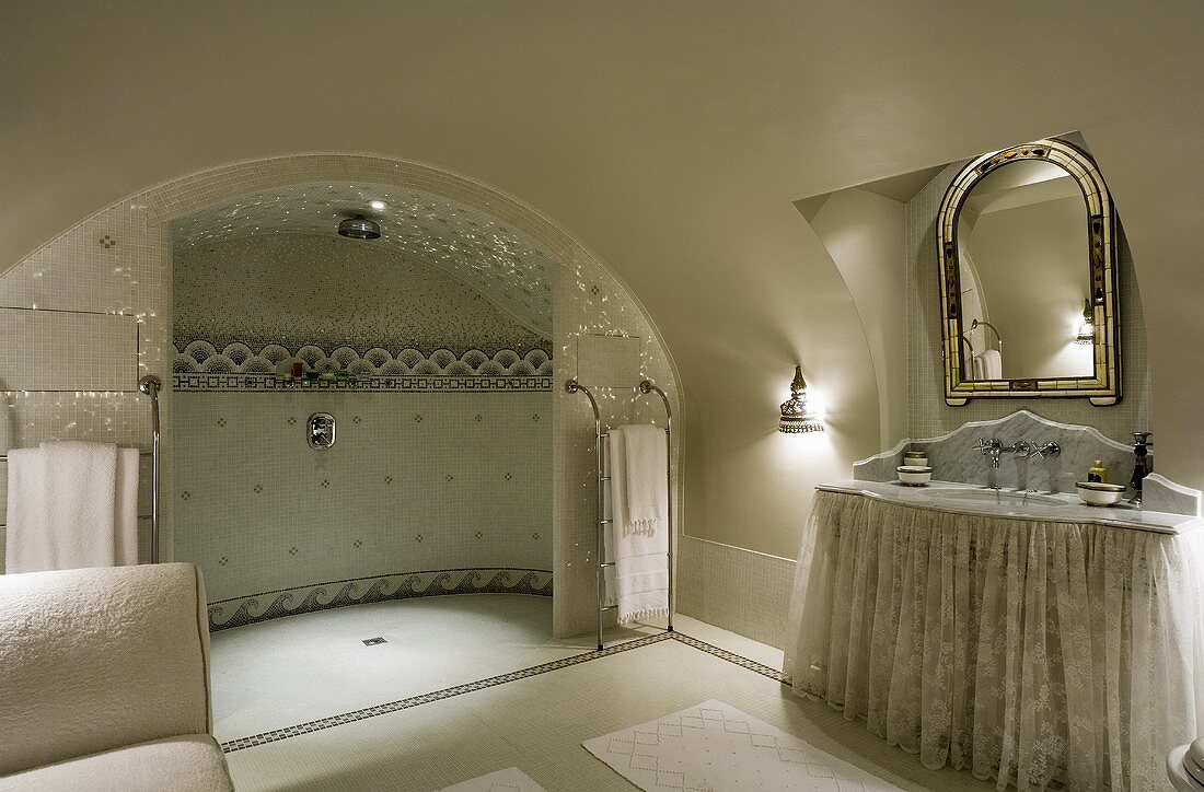 An elegant bathroom with a vaulted ceiling, a luxury shower area and a mirror above a marble topped washstand