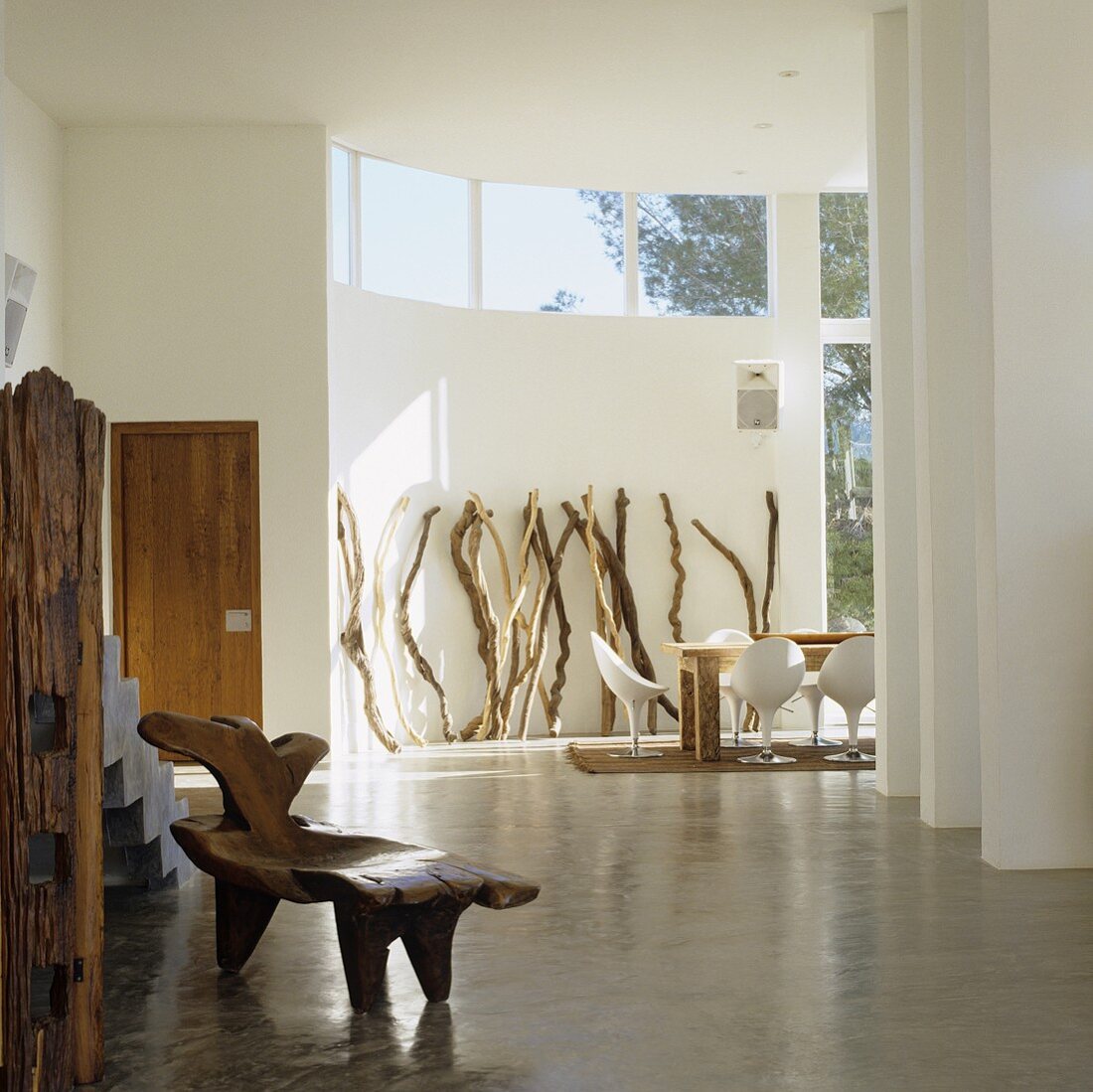 Mediterraner Designerhaus - rustikaler antiker Stuhl auf poliertem Estrich im offenen Wohnraum