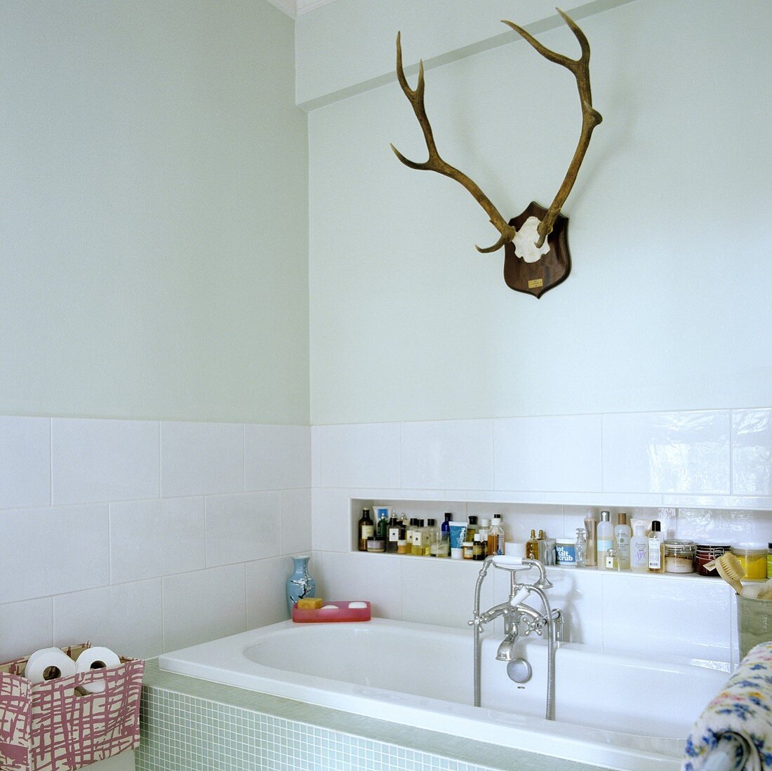 Hirschgeweih im weissen Bad mit Badewanne und Badutensilien in Nische