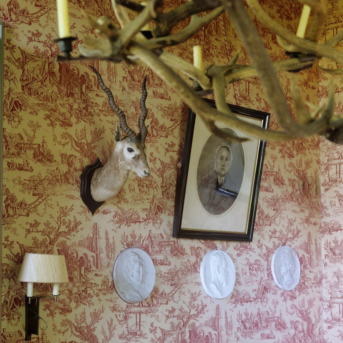 A stuffed animal head and a picture hanging on a wall with patterned wallpaper