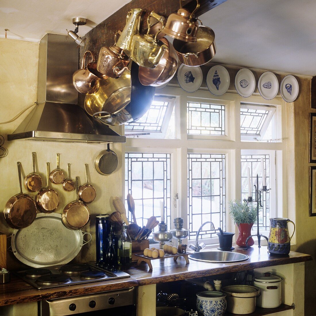 Copper pots hanging from a wooden ceiling beam in the kitchen of a country house