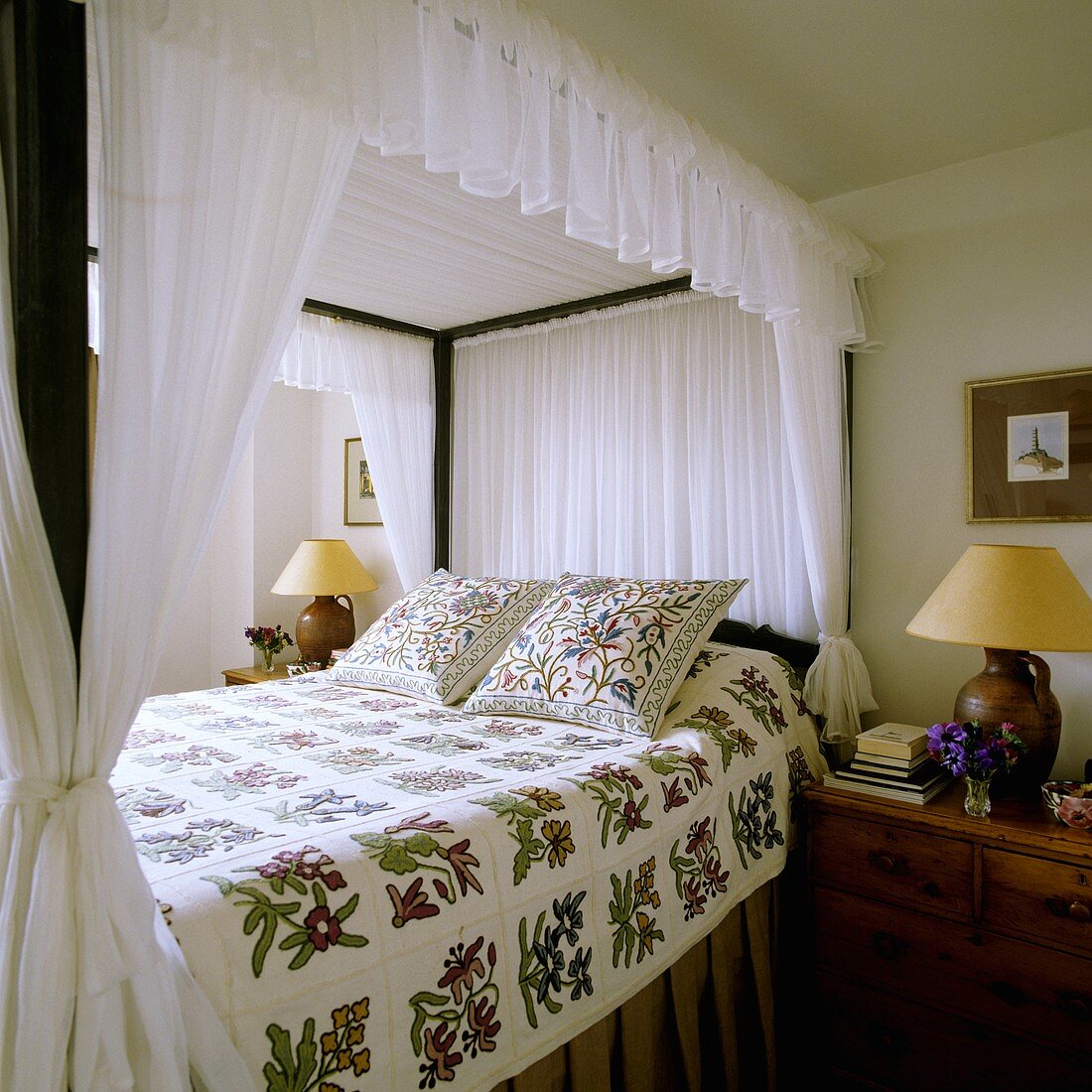 Himmelbett mit weißem Baldachin und Blumenmuster auf Tagesdecke und Kissen