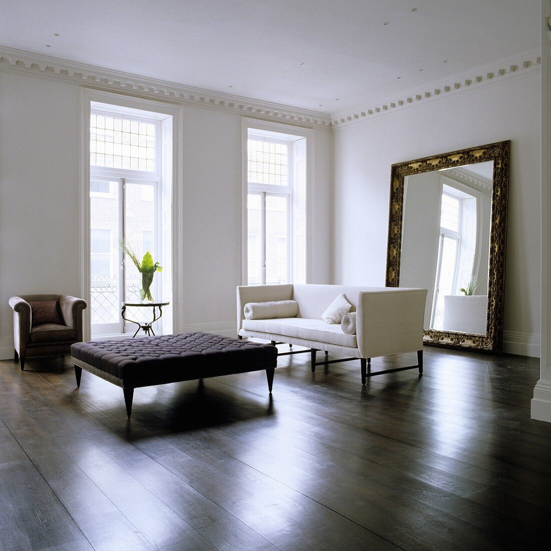 A minimalistic living room in a period building with a coffee table and a white sofa in front of a free-standing mirror