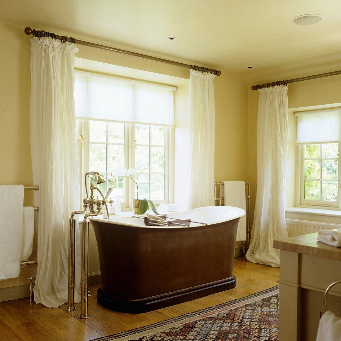 A bathroom in an old English country house with a free-standing bathtub and antique standing taps