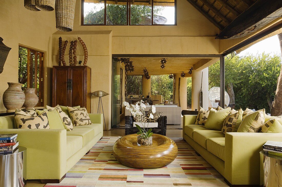 Hellgrüne Sofagarnitur und Bodentisch aus Holz vor Glasfront in südafrikanischer Villa