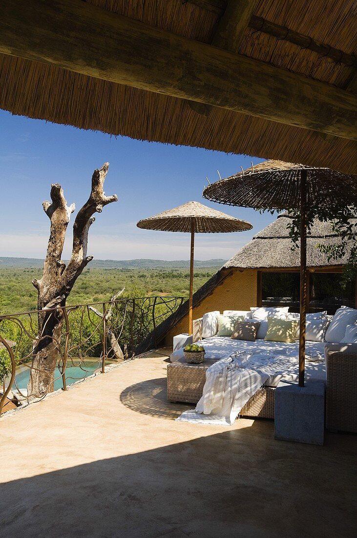 Südafrikanische Terrasse mit Bambusschirmen und gemütlichem Liegesofa