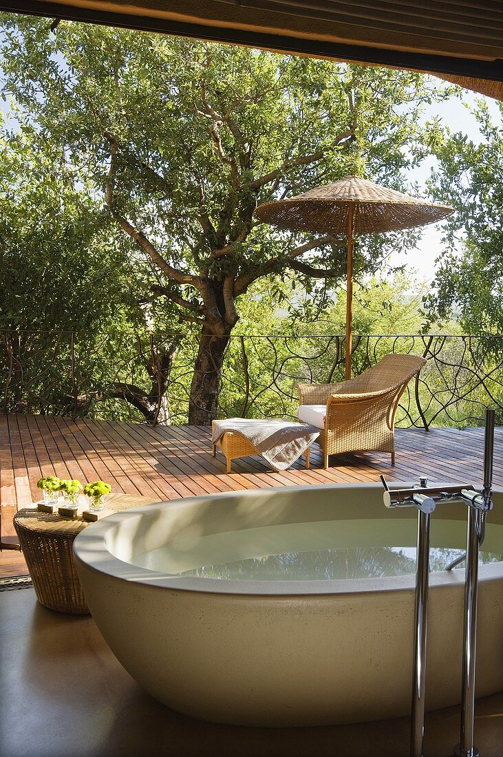 A free-standing bathtub in front of an open window onto the terrace of a South African house