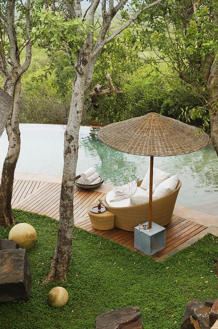 Südafrika - Bambusschirm und Korbsessel auf Holzterrasse am Pool im Garten