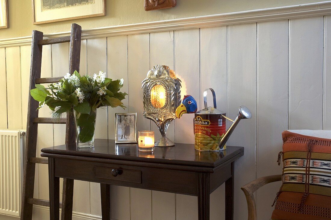 An antique wall table and a wooden ladder against white wood panelling